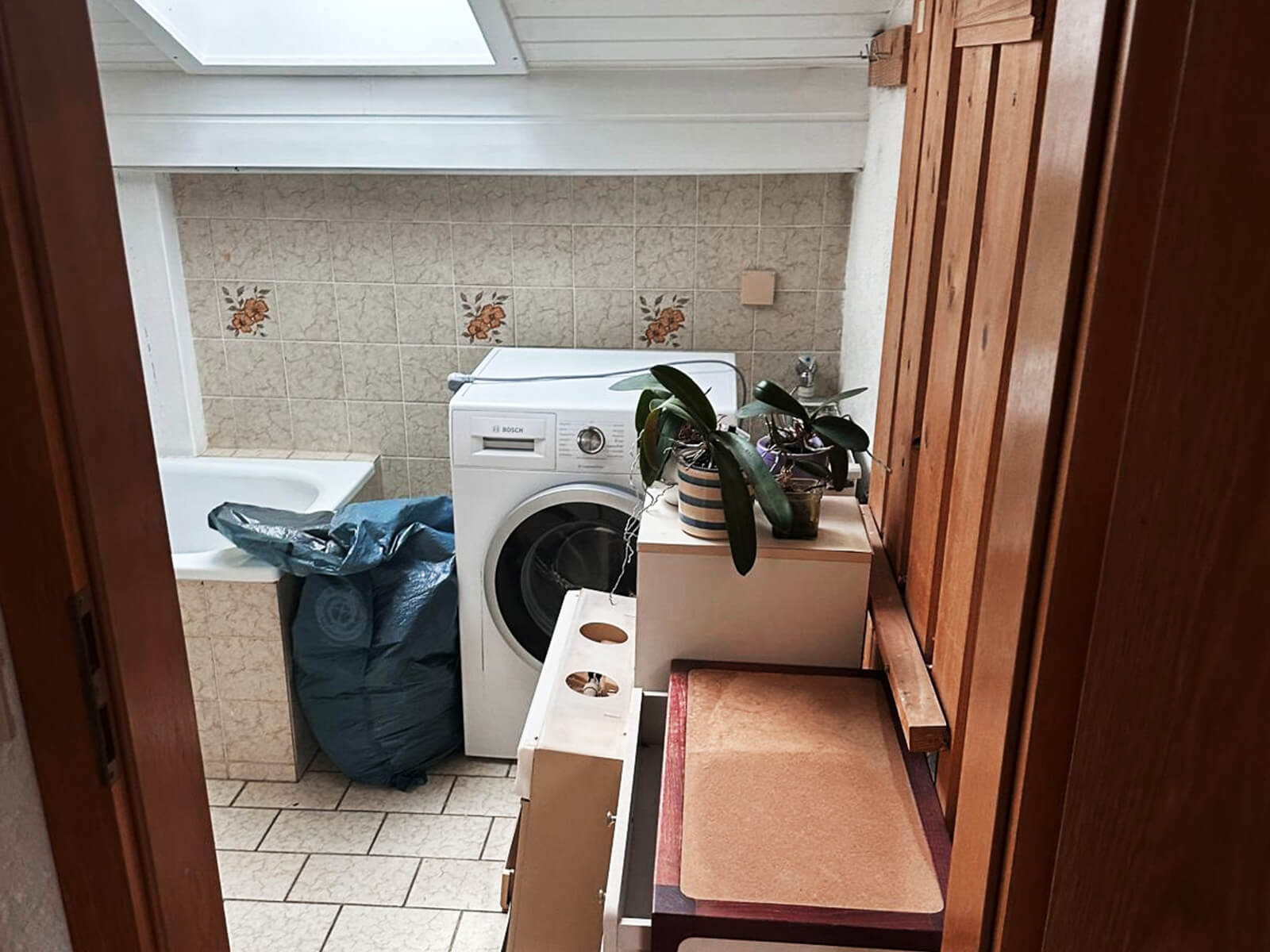 Vollgestelltes Bad mit Waschmaschine und Pflanzen